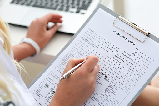 A woman filling out a new patient form at Alexandra Garcia, DDS, MS in Houston, TX